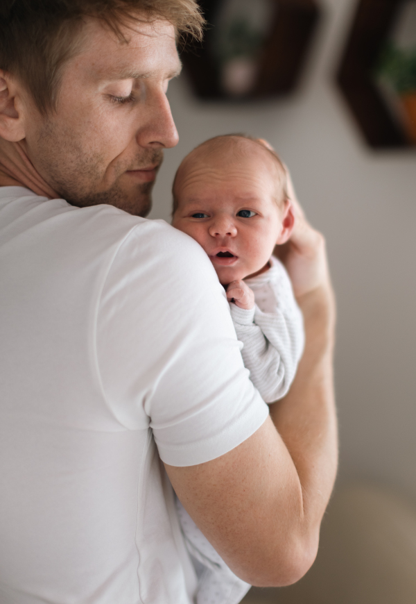 A father holding his newborn son at home.