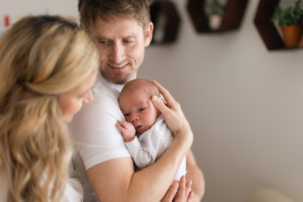 A happy mother and father holding their newborn baby daughter at home