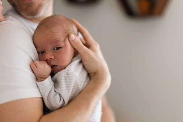 A father holding his newborn son at home.