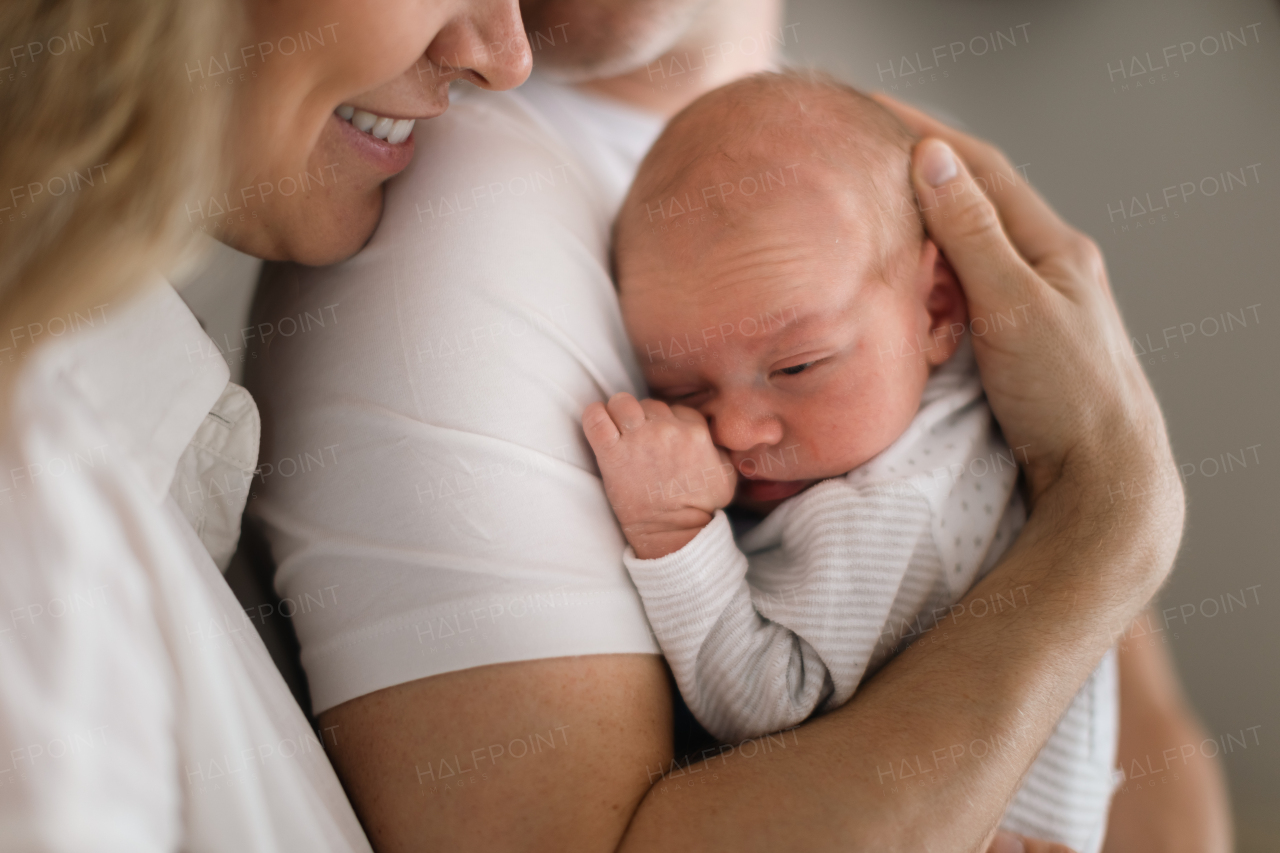 A smiling mother and father holding their newborn baby daughter at home