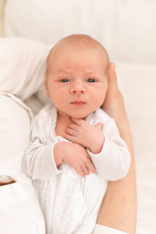 An unrecognizable mother holding her newborn son at home, close-up