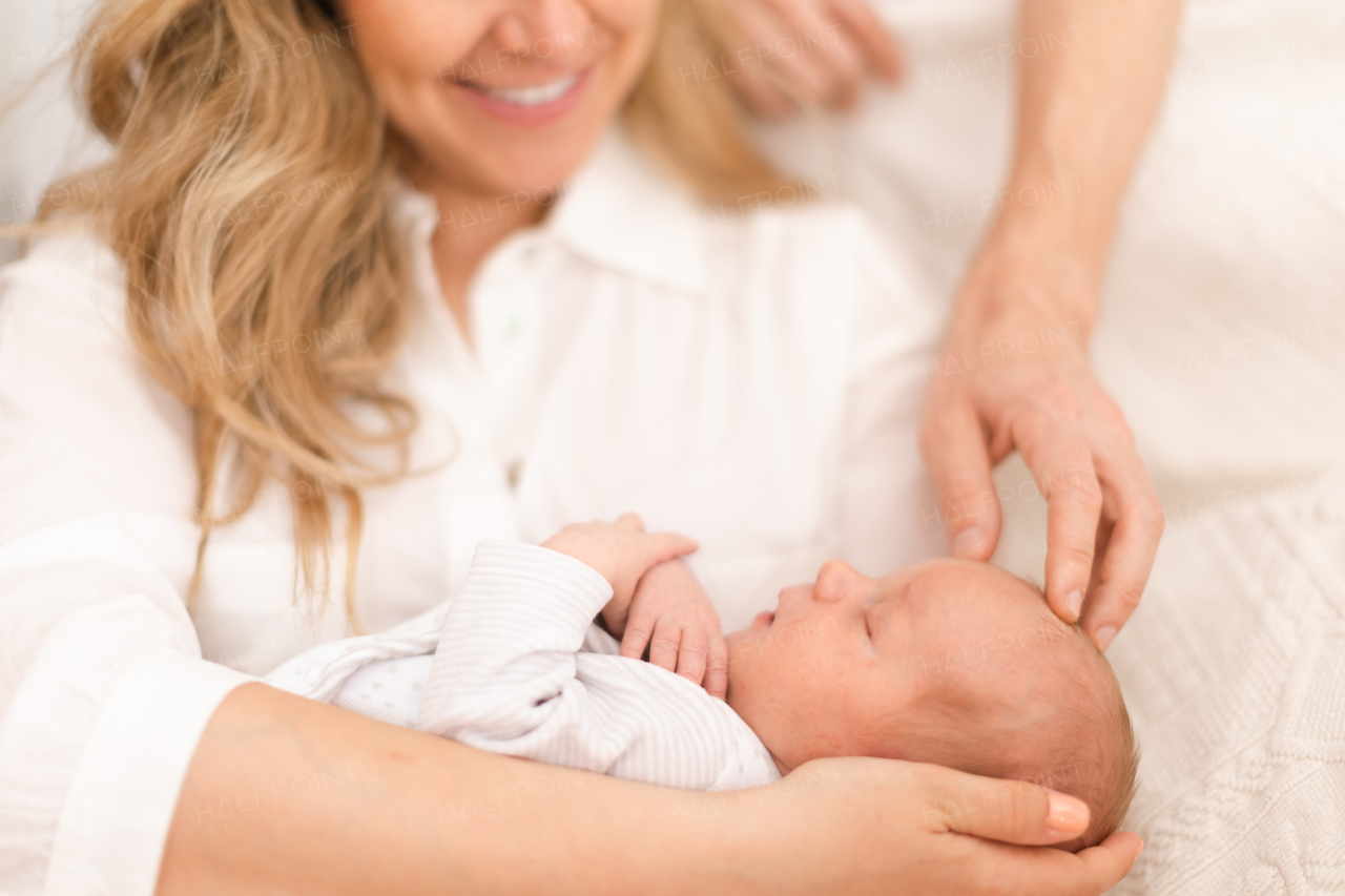 A close-up of mother and father holding their newborn baby son at home