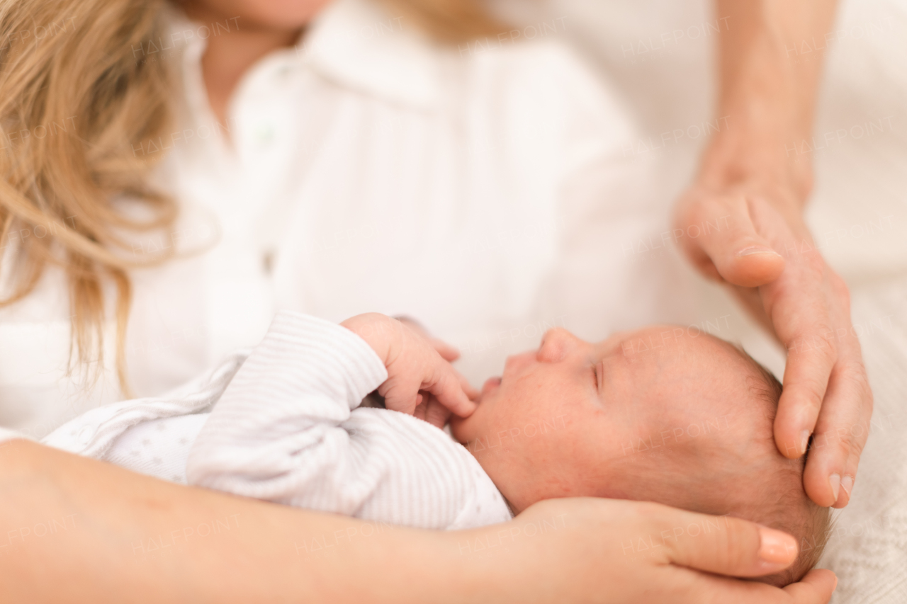 A close-up of mother and father holding their newborn baby son at home