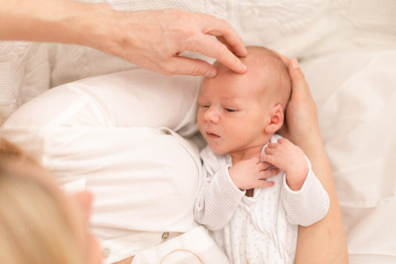 A close-up of mother and father holding their newborn baby son at home