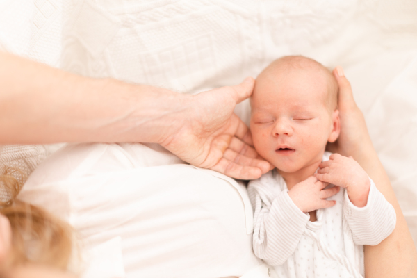 A close-up of mother and father holding their newborn baby son at home