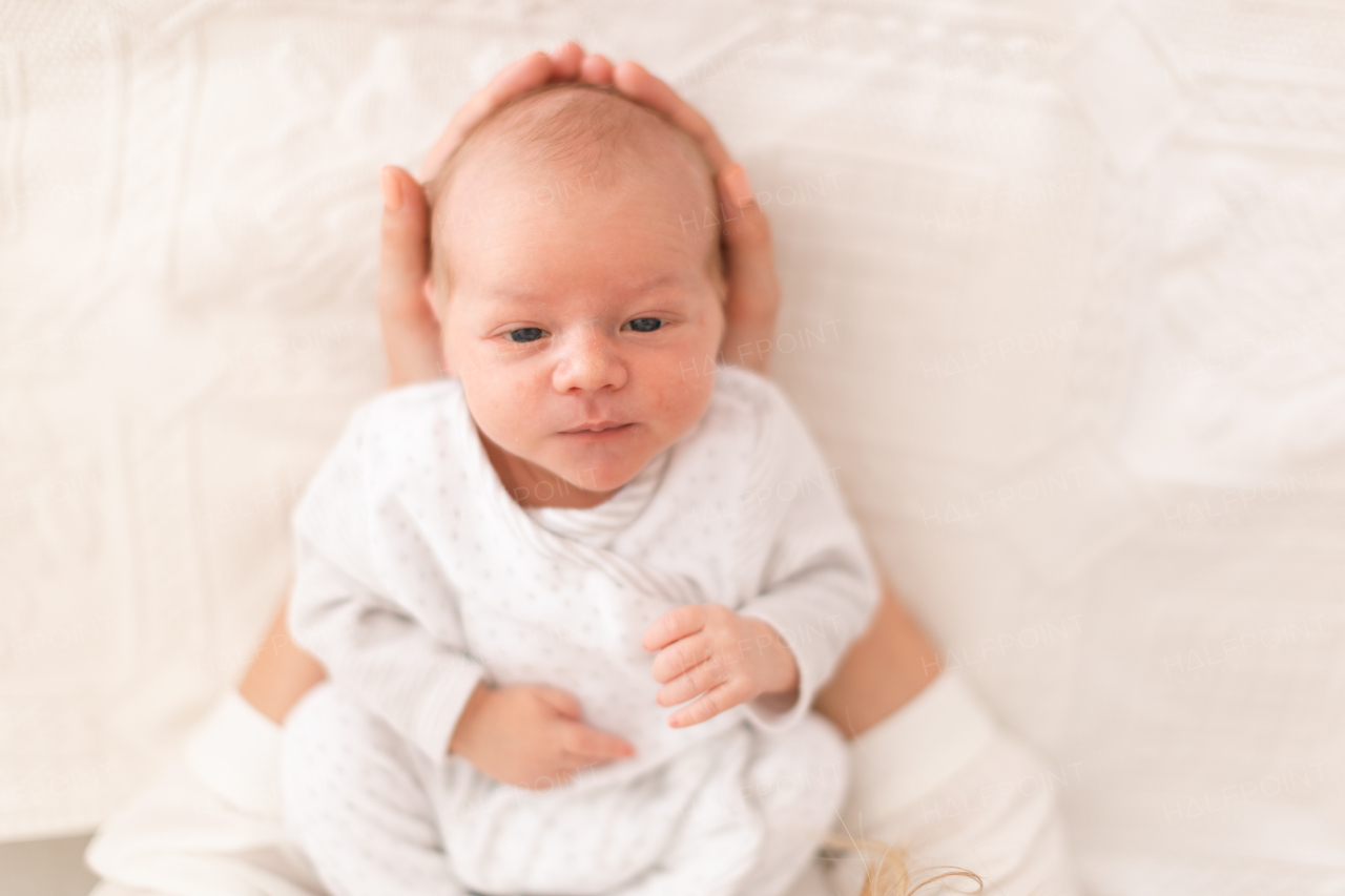 An unrecognizable mother holding her newborn son at home, close-up