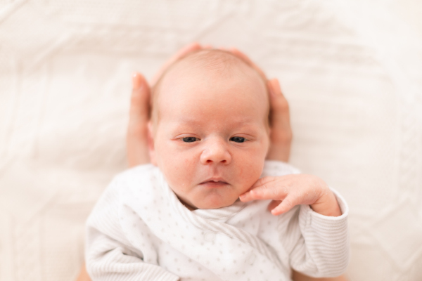 An unrecognizable mother holding her newborn son at home, close-up