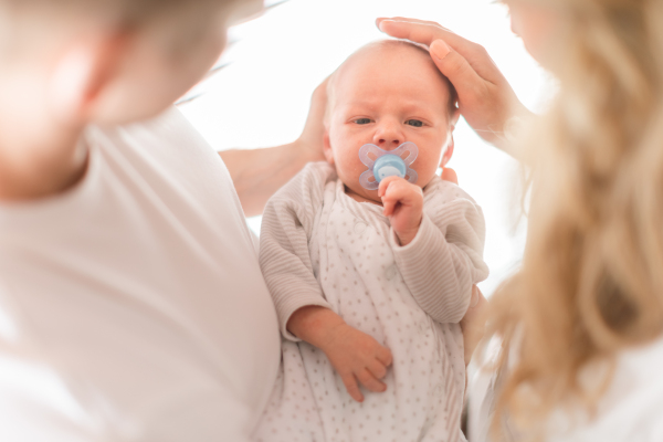 A close-up of mother and father holding their newborn baby son at home