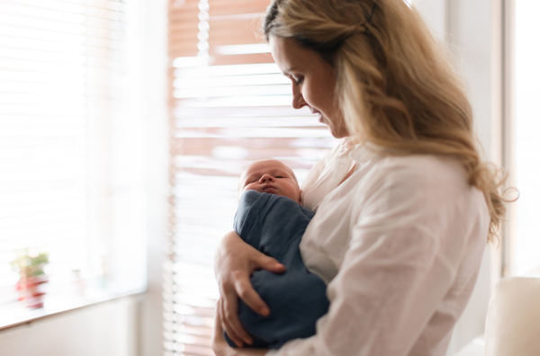 A young mother holding her newborn son at home.