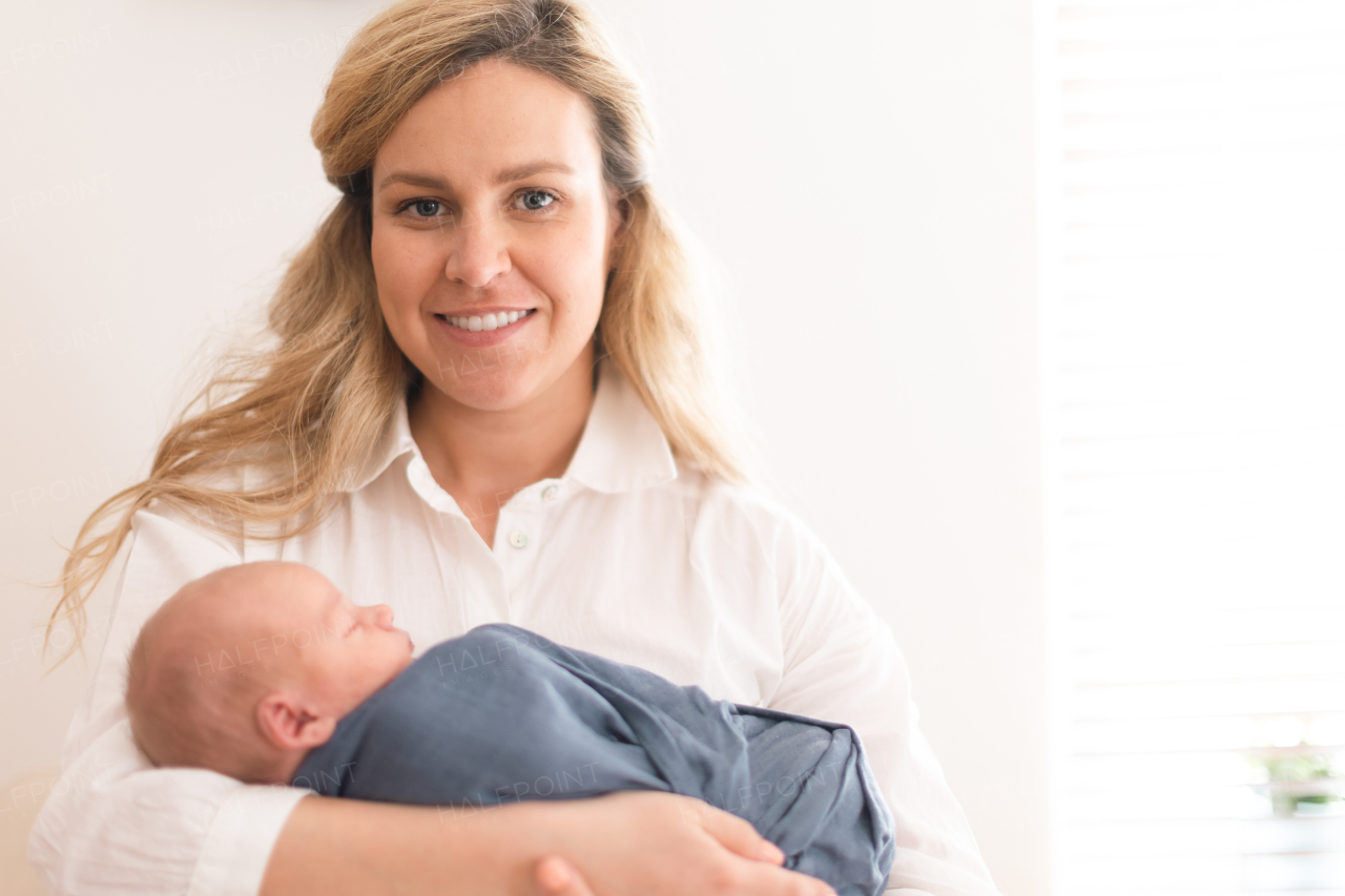 A young mother holding her newborn son at home.