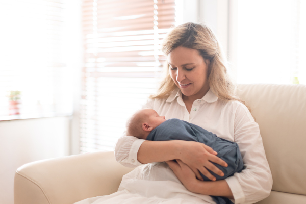 A young mother holding her newborn son at home.