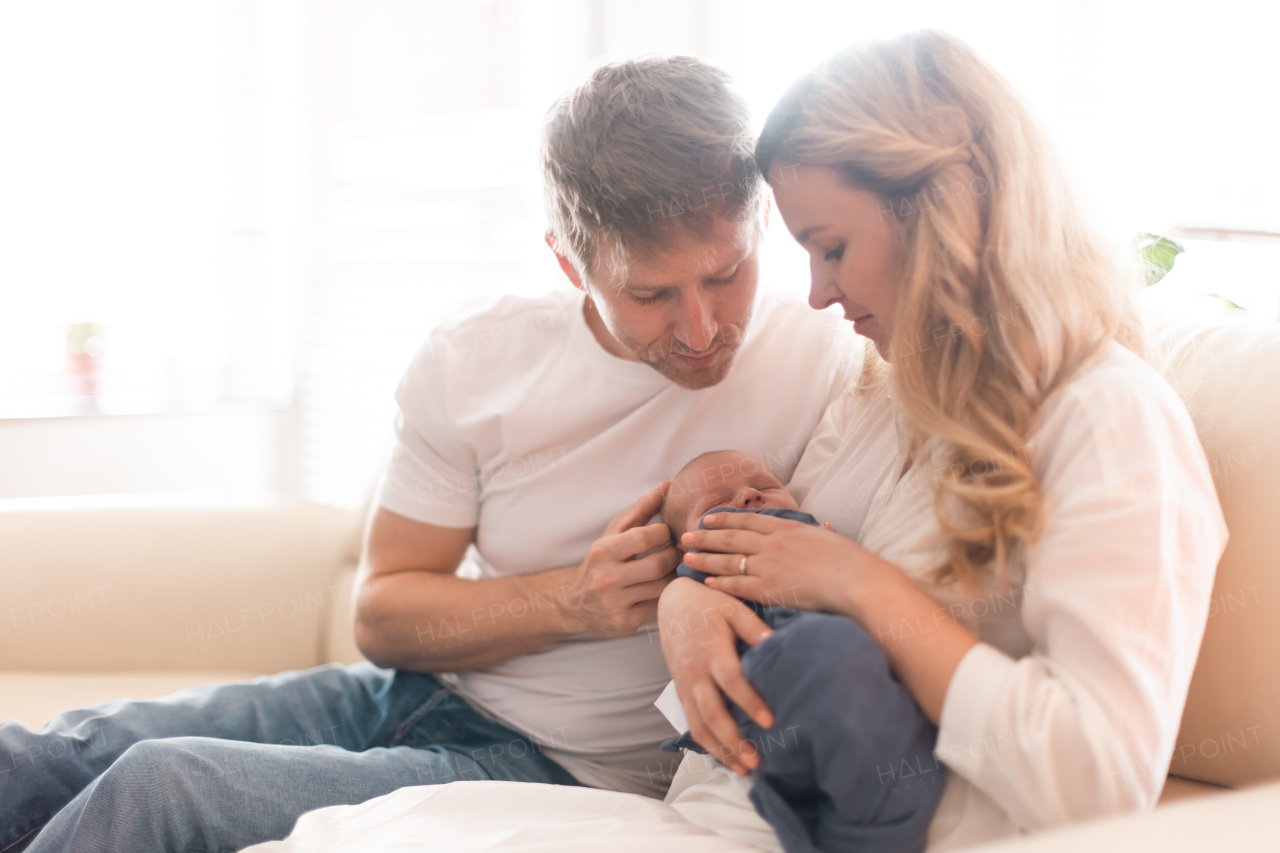 A smiling mother and father holding their newborn baby daughter at home