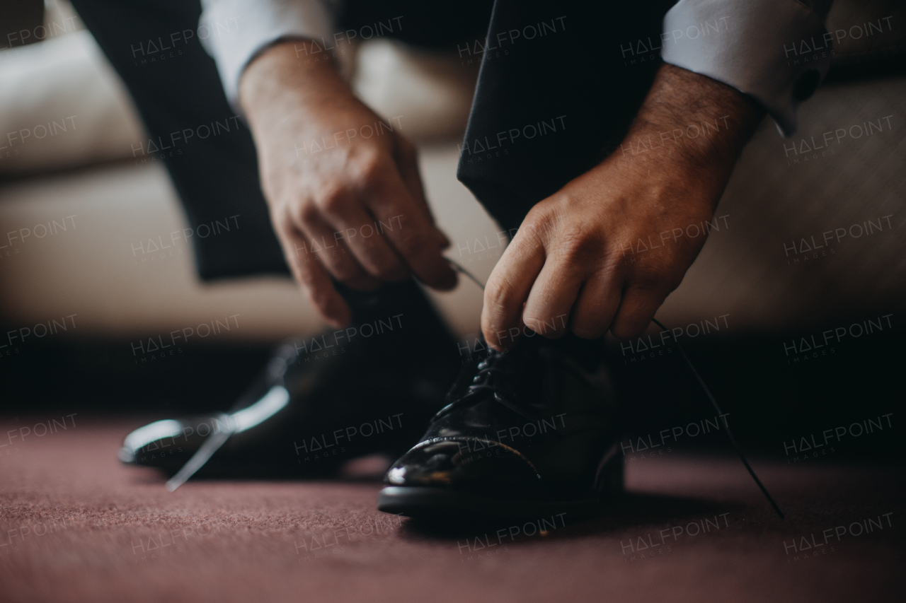 Close up of groom putting on a shoes, in the morning before wedding, tying shoelaces. Businessman in suit getting ready for work and business meeting.