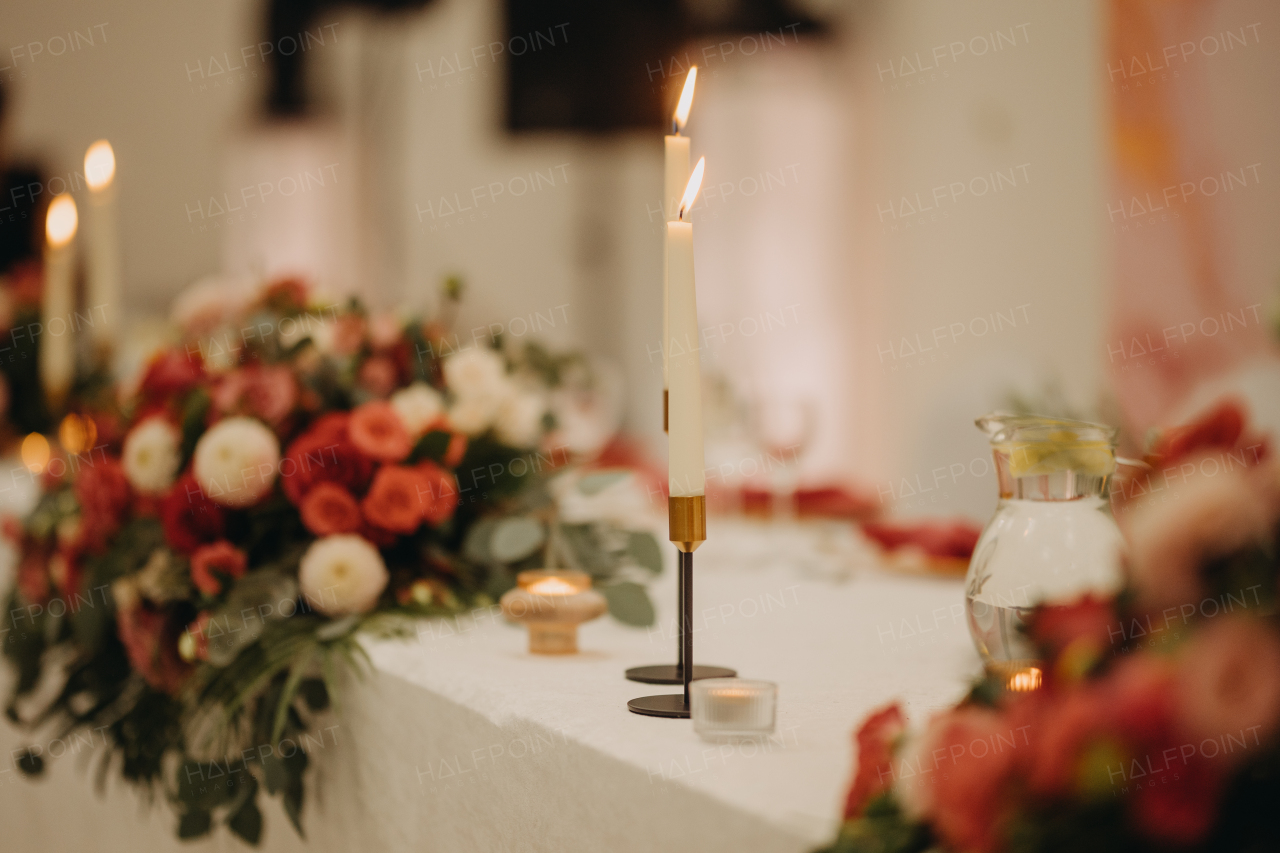 Elegant, romantic table setting for indoor wedding reception, celebration. Luxury wedding table decoration, special event table set up with fresh flowers arragements and high candlestick, candle holder.