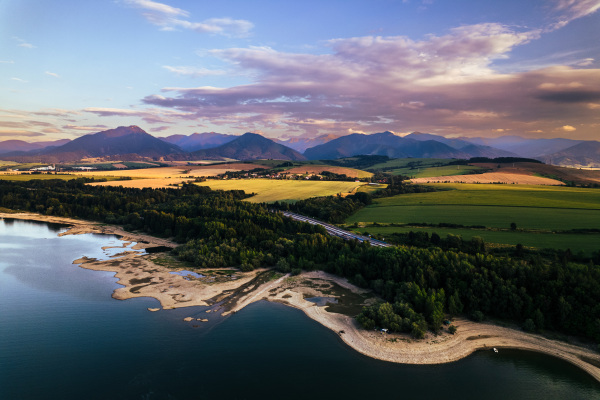 Aerial view from above the water surface of Liptovska Mara water reservoir on serene nature landscape, Low Tatras in the distance.