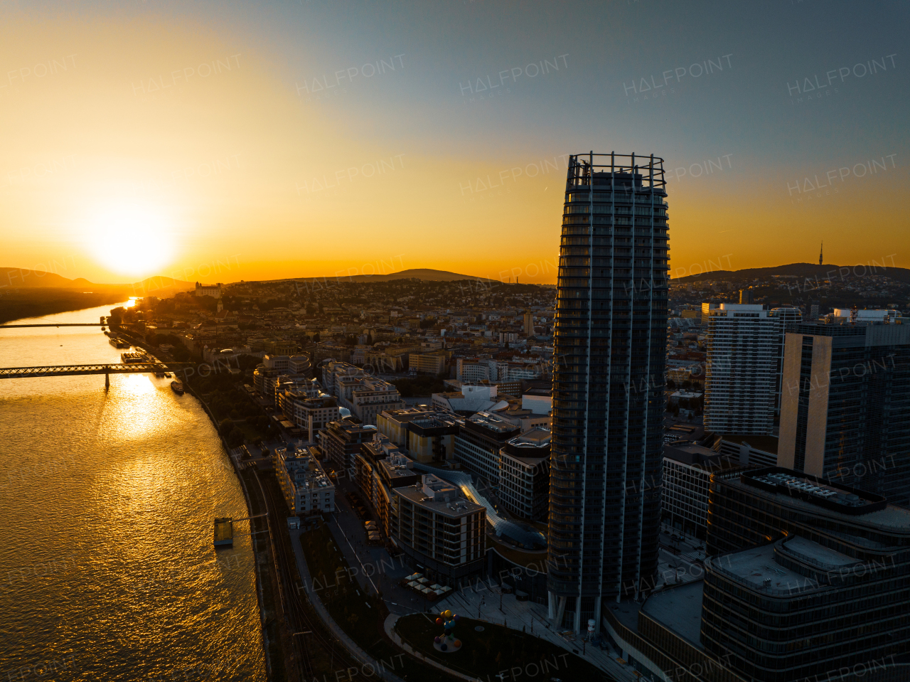 Aerial view of Bratislava city with riverbank of Danube river, during sunset.