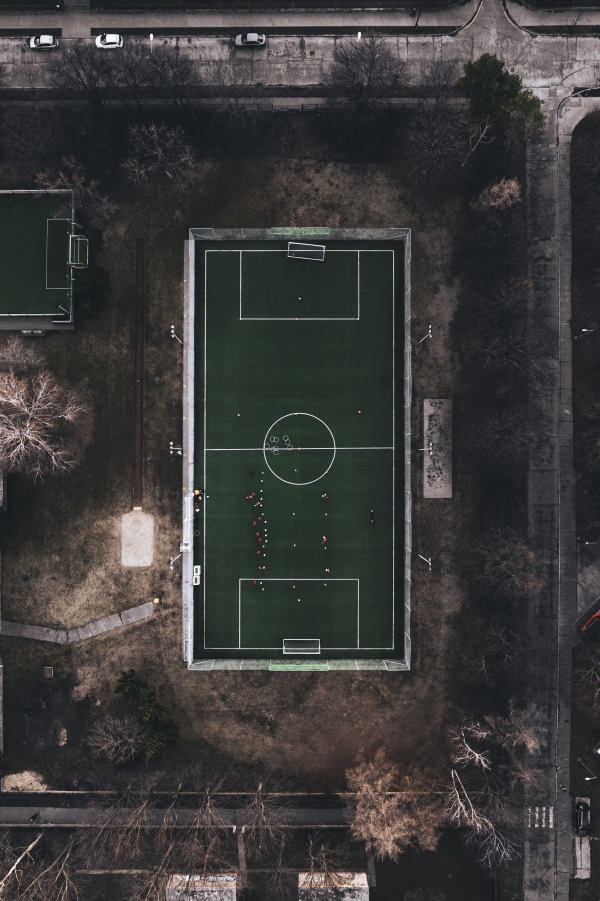 Top view of a small training football field in city. Soccer pitch with artificial turf in urban setting during cold winter day without snow.