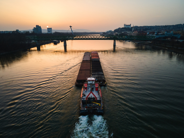 Aerial view of cargo ship sailing on the Danube through Bratislava. The Danube river and passage under river bridges.