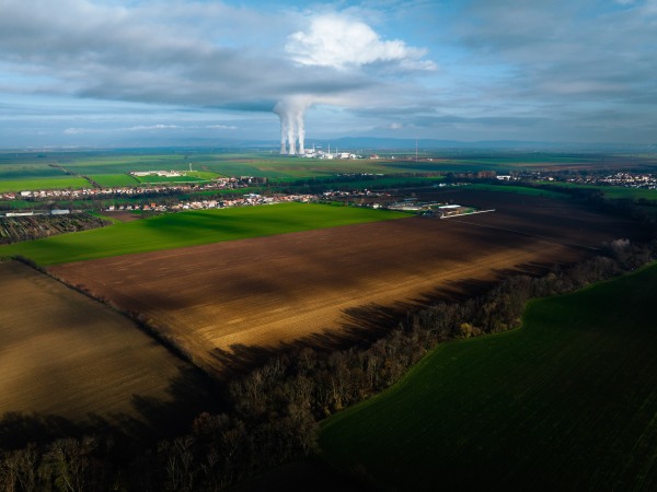 Aerial view of nuclear power plant with towering cooling towers emitting steam.