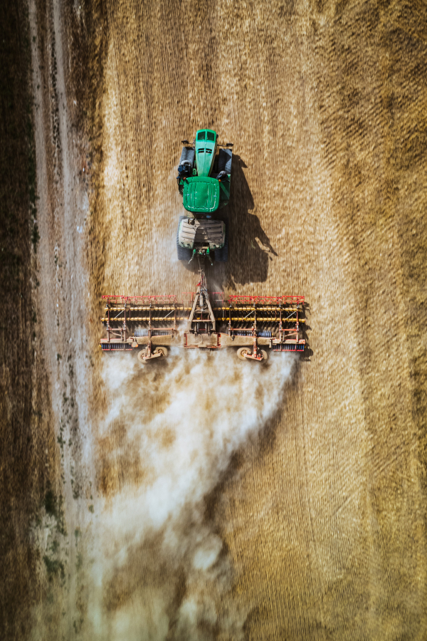 Aerial view of a harvester working on field. Agriculture and cultivation of industrial farms. Agribusiness.