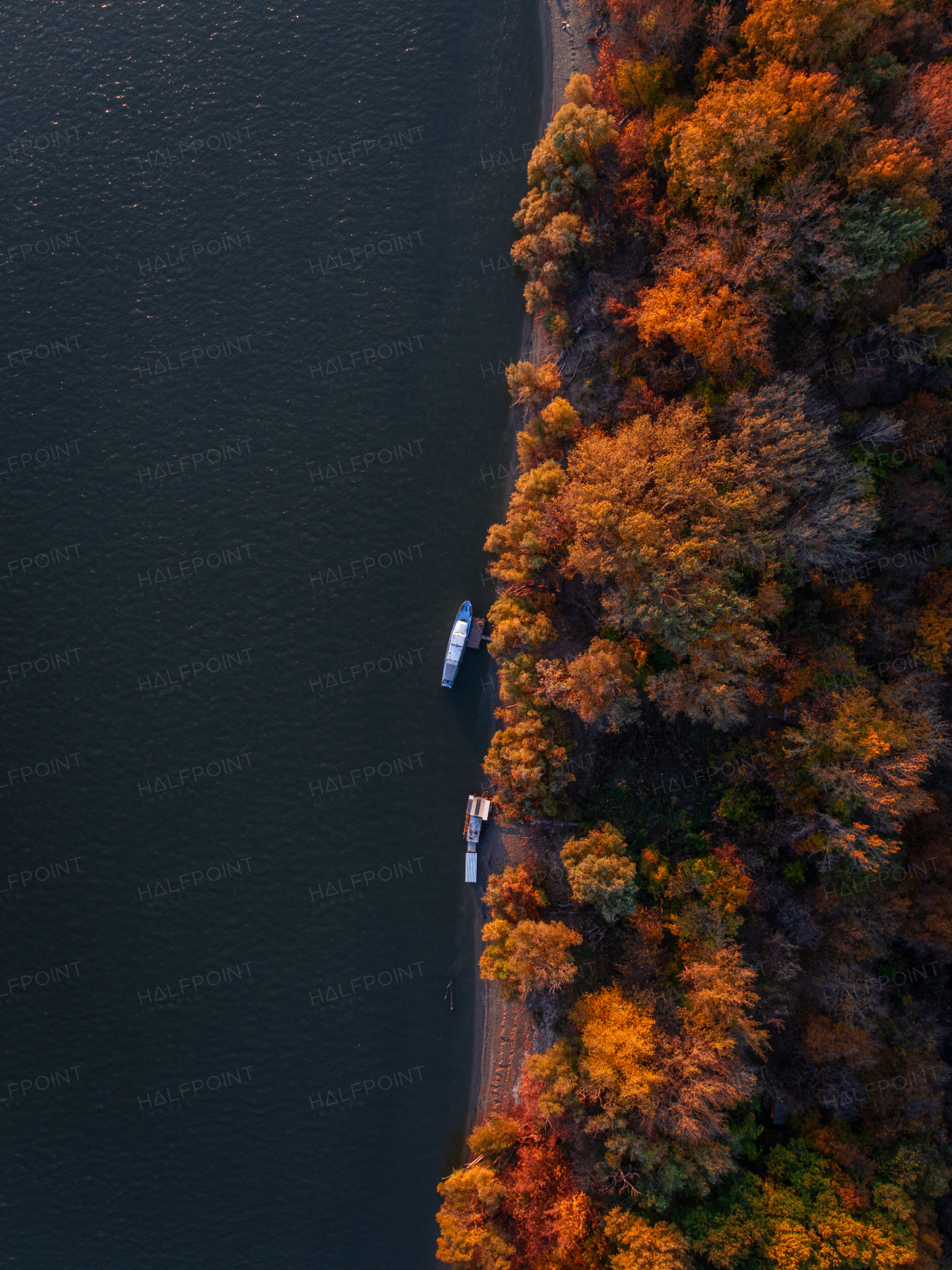 Top view of lake shore with two small boats, surrounded by autumn forest with sand beach, coastline.