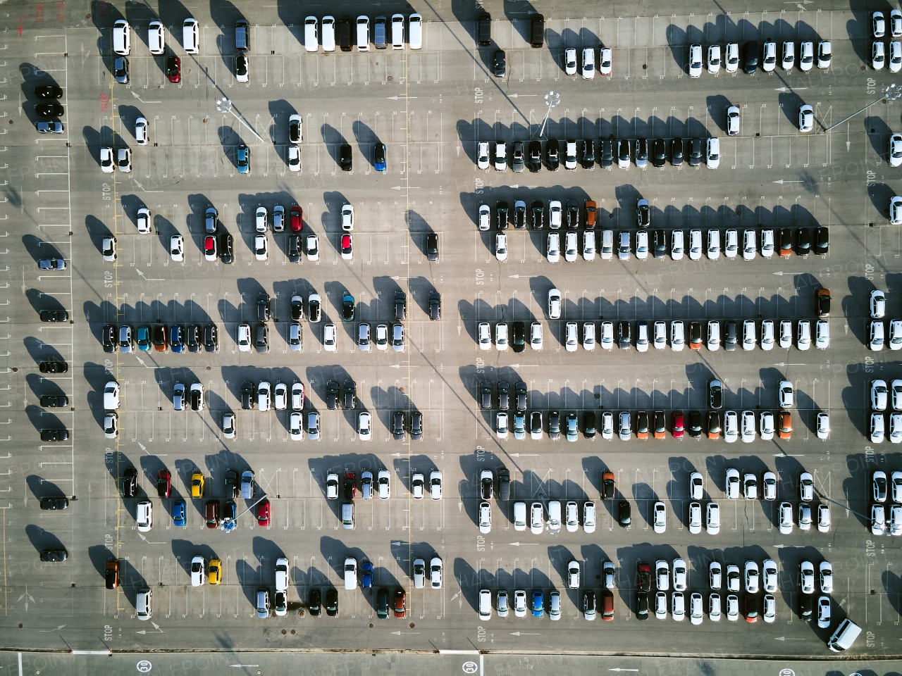 Aerial view of massive parking lot at a car manufacturing facility with newly produced vehicles parked in rows.