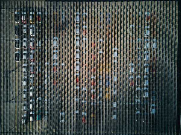 Aerial view of massive parking lot at a car manufacturing facility with newly produced vehicles parked in rows.