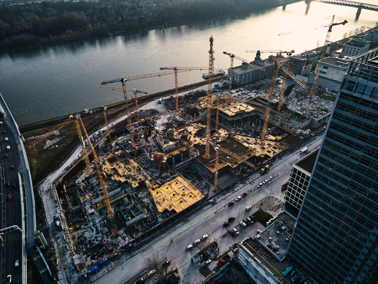 Top view of construction site with cranes in the city, by river. Areal photography, modern municipal or urban engineering.