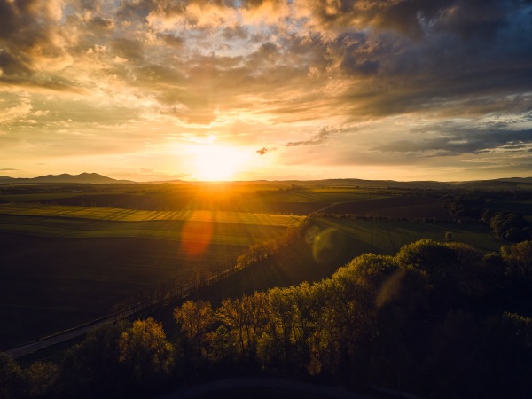 Aerial view of a meadows, forest and fields during sunset.