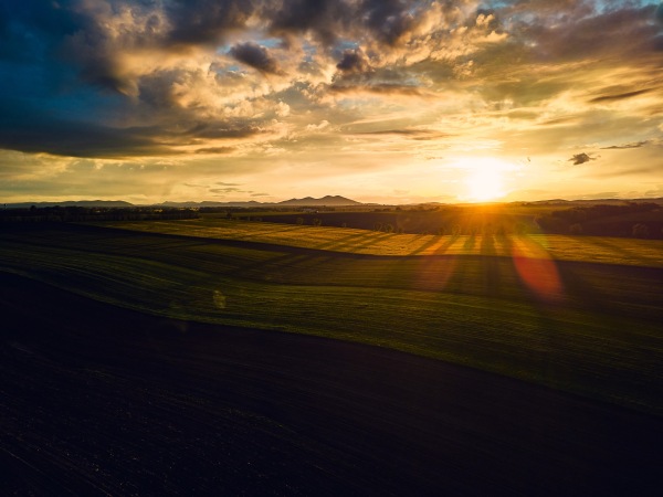 Aerial view of a meadows, forest and fields during sunset.