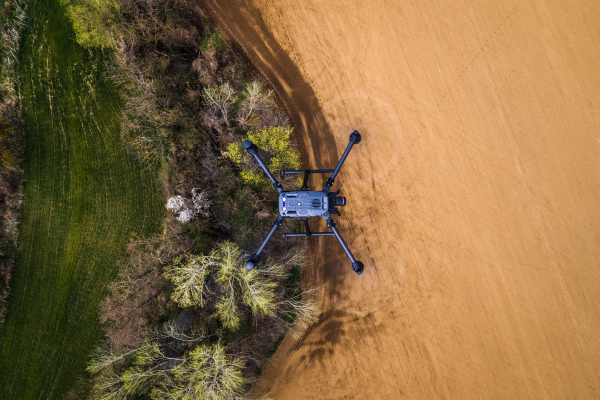 Aerial view of a drone flying over green summer farm fields, crops or pasture with road and mountains.