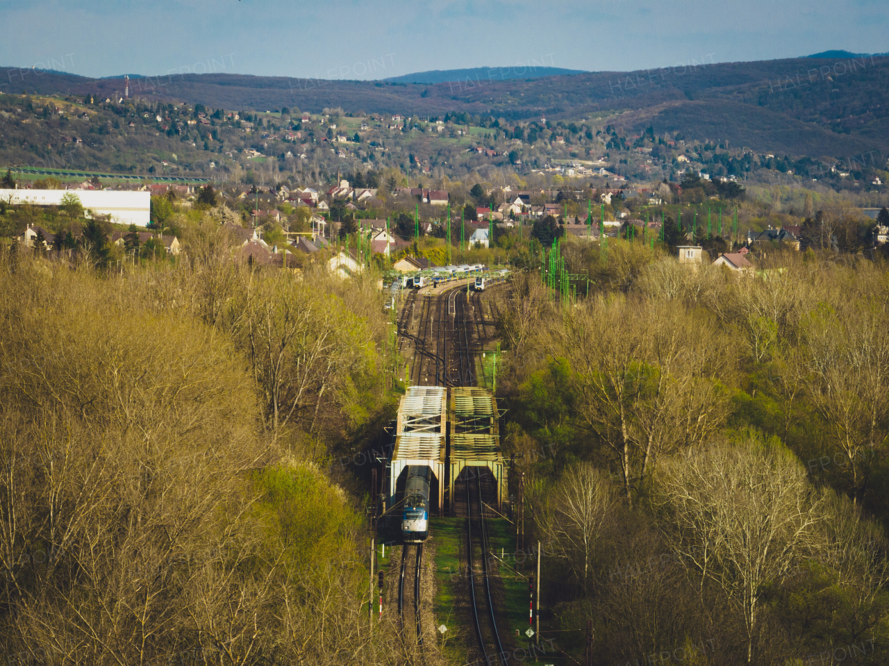 Aerial view of a blue train in the middle of nature, field, during autumn sunny day.