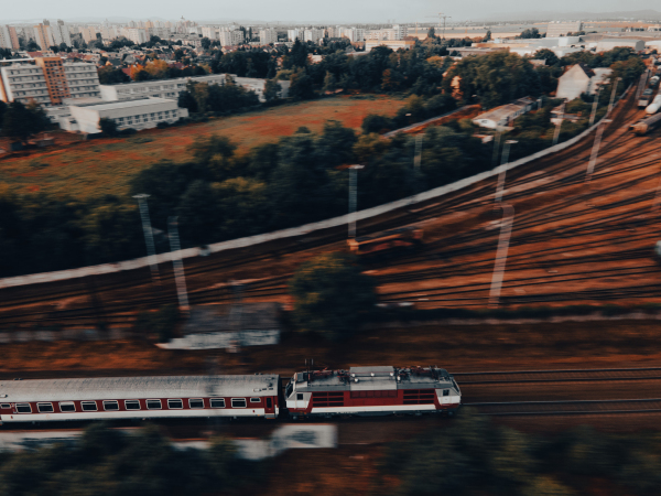 Aerial view of a train in the middle of nature, field, during autumn sunny day.