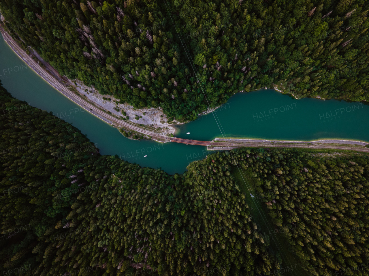 Aerial view of big metal railway bridge across river, in the middle of summer forest, no train.