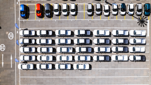 Aerial view of parking lot at a car manufacturing facility with newly produced vehicles parked in rows.