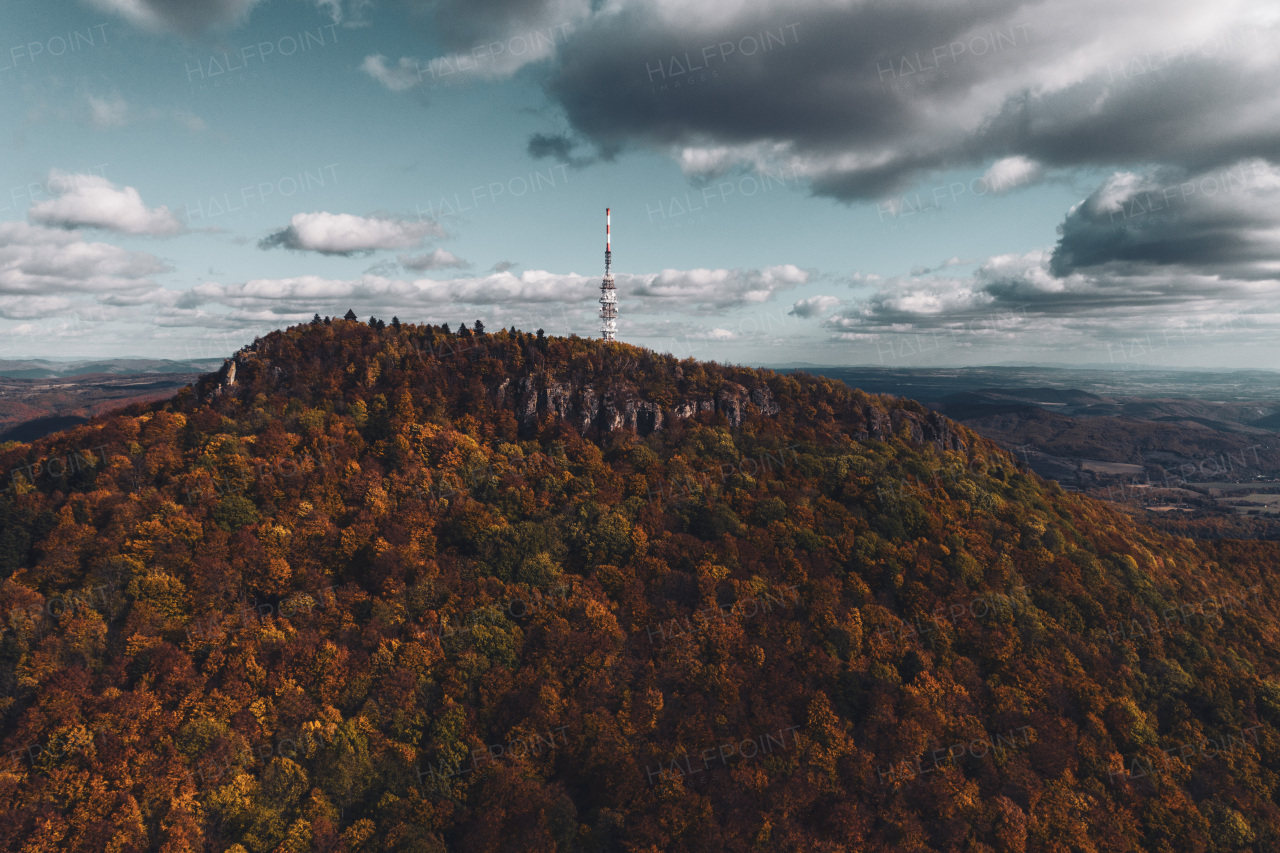 Aerial view of a transmitter, cell tower surrounded by a forest, clouds and fog. Drone view of landscape during sunset, sunrise.