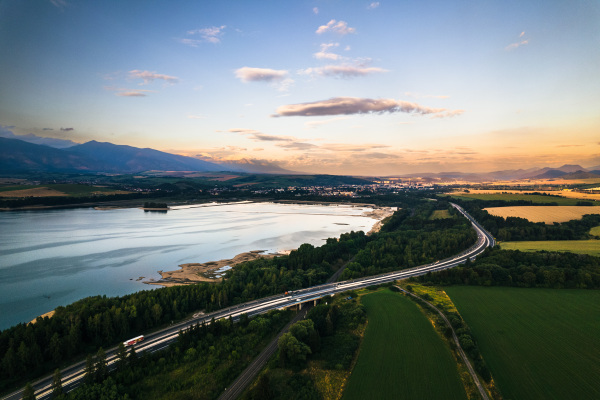 Aerial view from above the water surface of Liptovska Mara water reservoir on serene nature landscape, High Tatras Mountains in the distance.