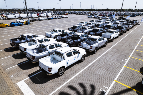 Aerial view of massive parking lot at a car manufacturing facility with newly produced vehicles parked in rows.