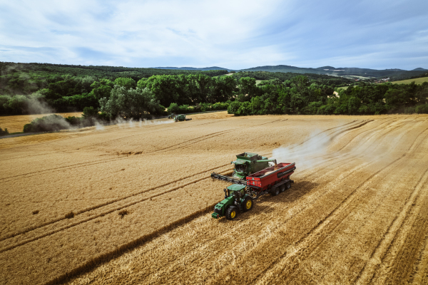 Aerial view of a tractor a harvester working on field. Agriculture and cultivation of industrial farms. Agribusiness.