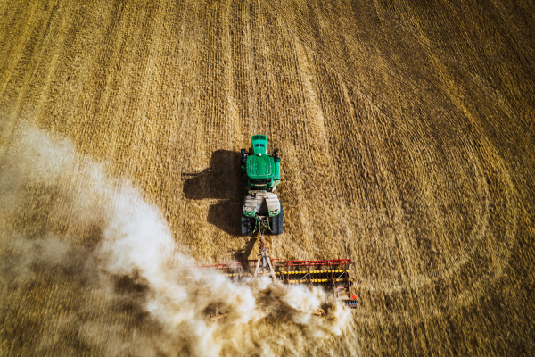 Aerial view of a harvester working on field. Agriculture and cultivation of industrial farms. Agribusiness.