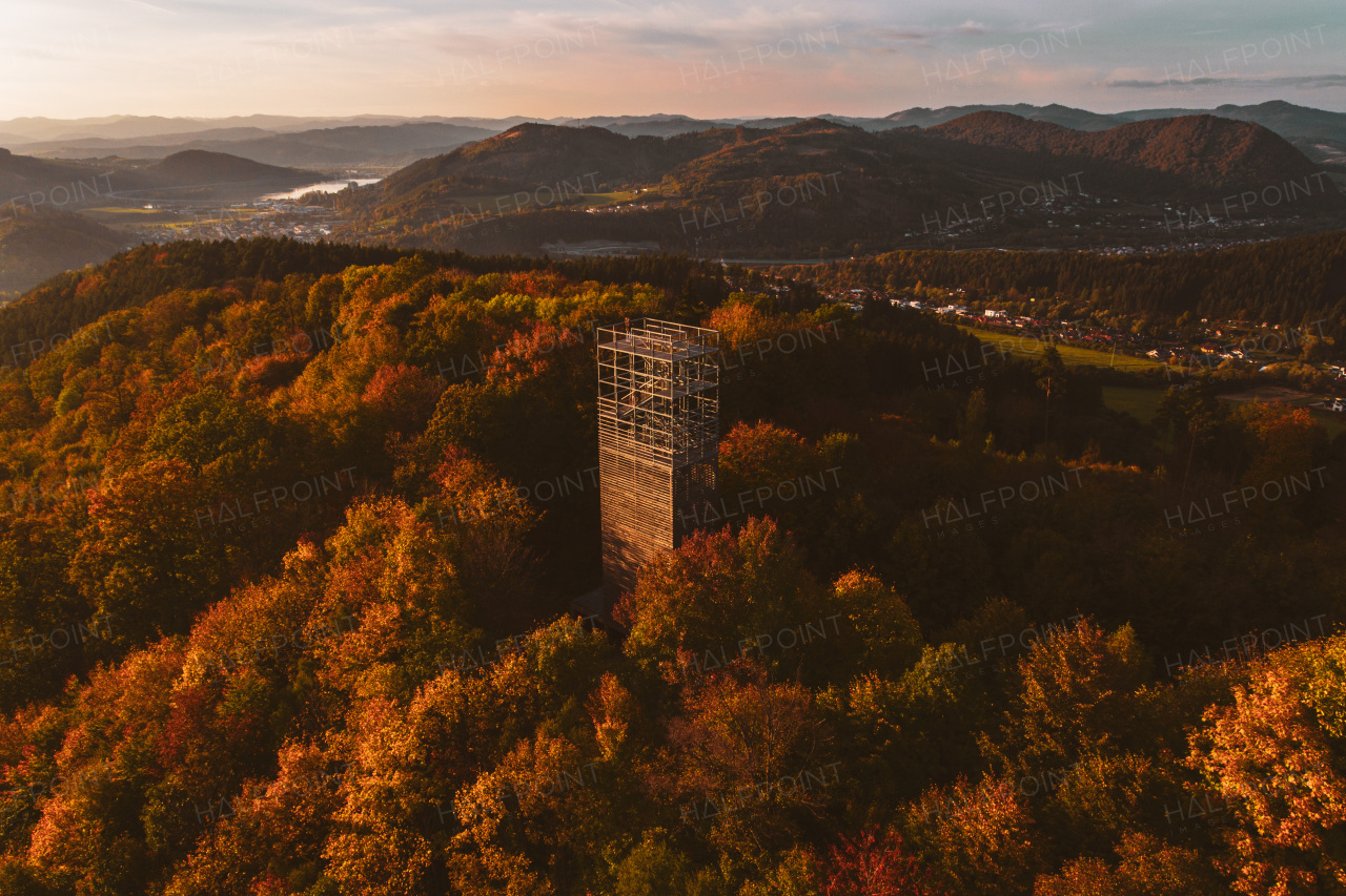 Aerial view of wooden lookout tower in autumn nature. People stand on the observation tower, enjoying beautiful, serene view of the surrounding landscape.