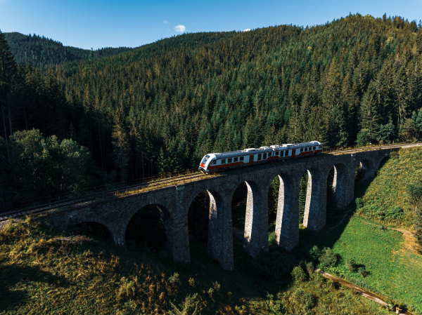 Aerial view of the train on historical stone railway bridge in Slovakia. High, fully preserved stone arch railway bridge.