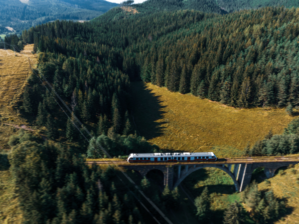 Aerial view of the train on historical stone railway bridge in Slovakia. High, fully preserved stone arch railway bridge.