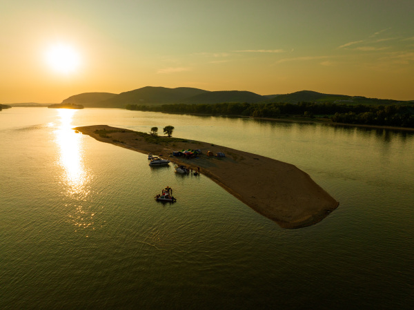 Top view of small river island, surrounded by water during warm summer sunset. Camping on riverine or lake island.