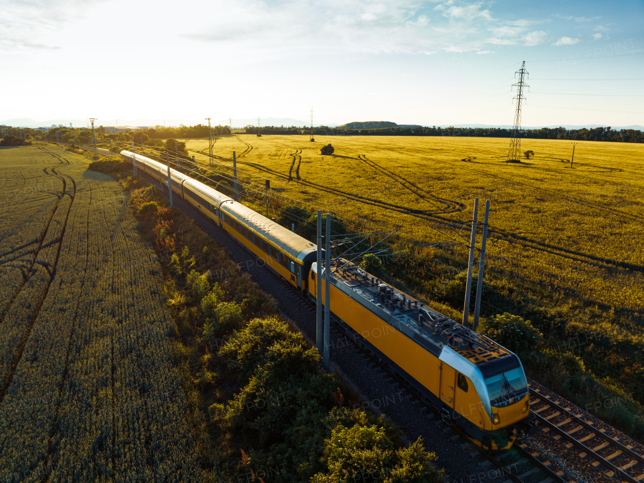 Aerial view of a yellow train in the middle of nature, field, during autumn sunny day.