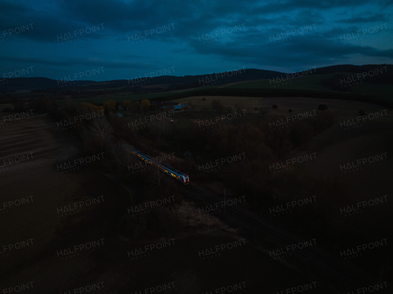 Aerial view of a blue train in the middle of nature, field, during night. Night train.