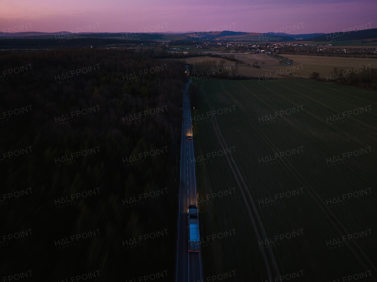 Aerial view of night summer farm fields, crops or pasture with road and mountains.