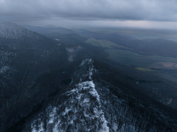 Aerial view of old ruins of fortress in the middle of winter forest. Drone view of snowy landscape with broken stone walls. Castle ruins.