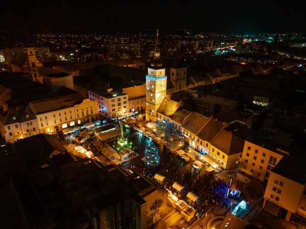 Aerial night shot of city during Christmas, winter and christmas decorations on city square. Chistmas market during holiday season in small city.