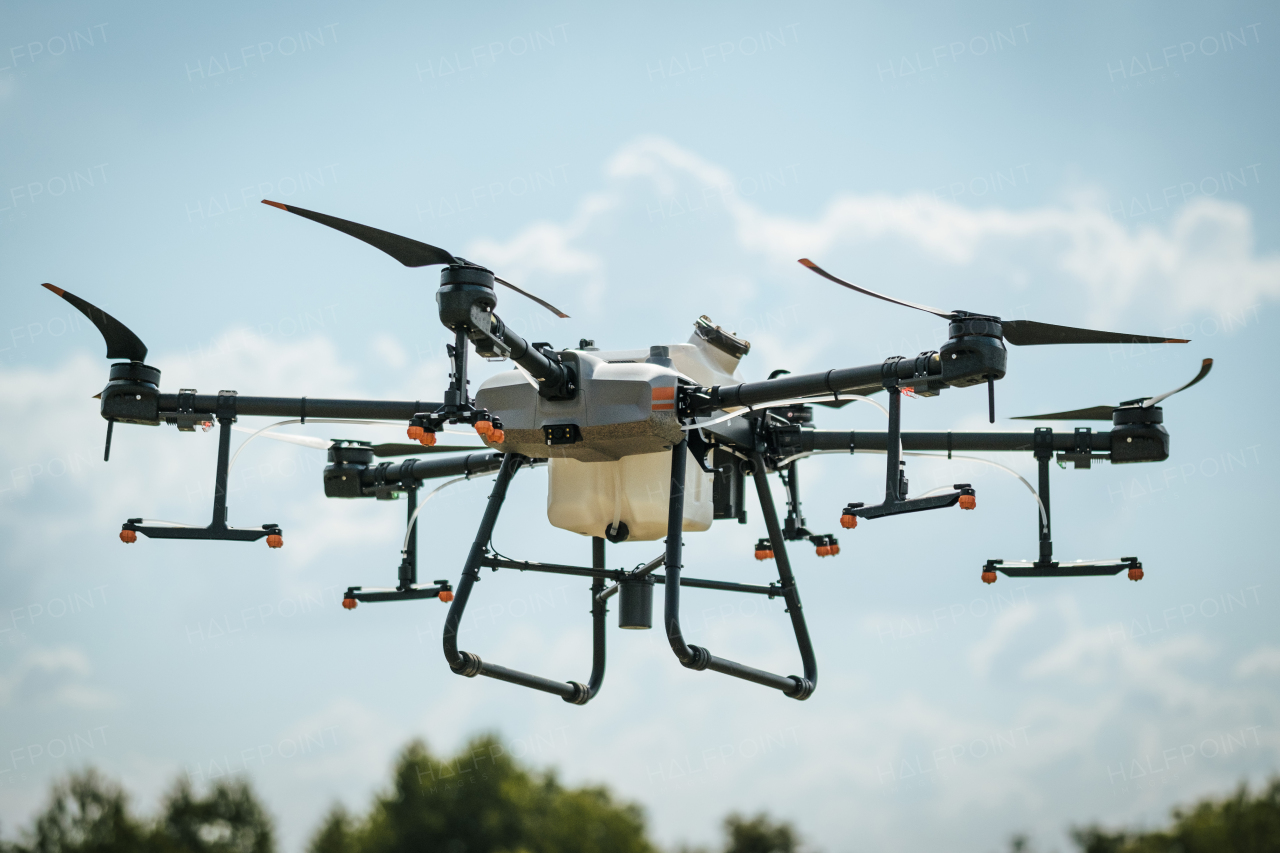 Close up of agricultural drone with spray nozzles and tank. Dron spraying crops, distribute pesticides, herbicides and fertilizers efficiently and precisely. Technologies in modern farming.